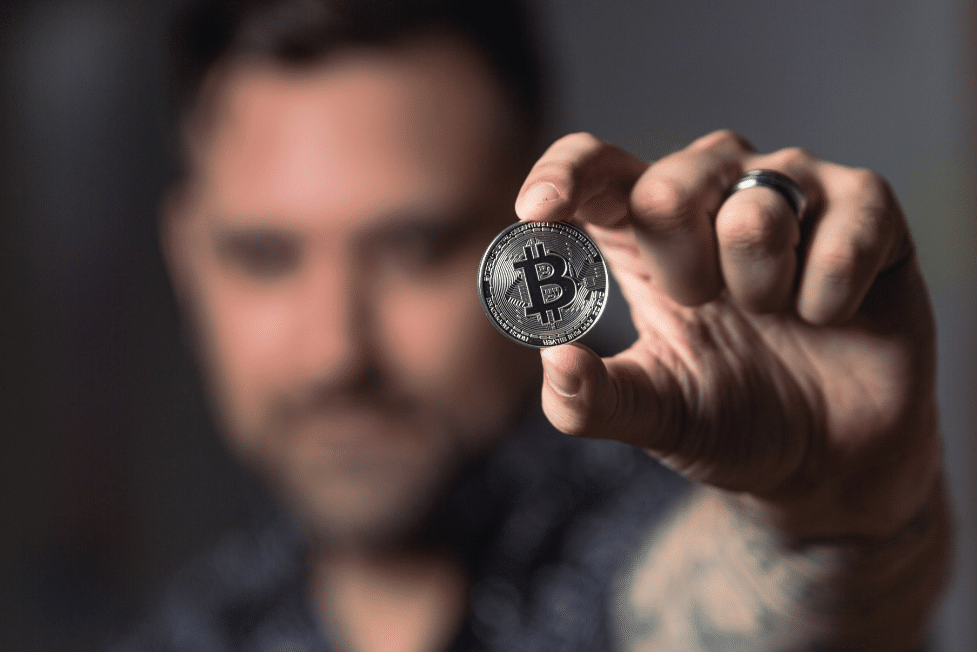 Man holding a bitcoin roughly worth one satoshi (2 cents)